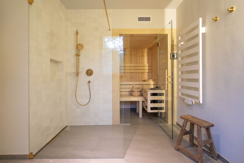 Bild Badezimmer mit ebenerdiger Dusche, Sauna und goldenen Armaturen.